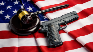 A handgun and a judges gavel rest on an American flag